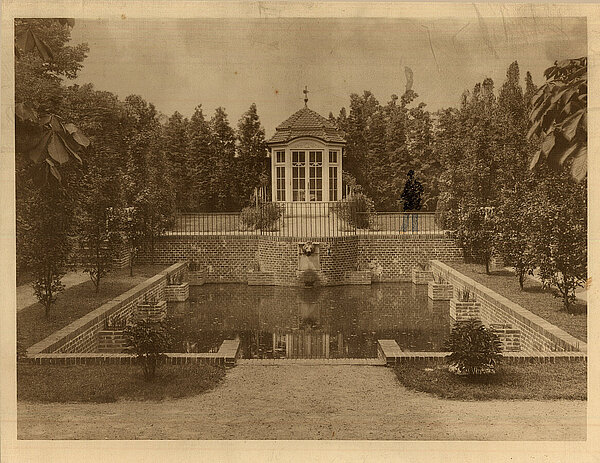Blick auf Wasserbecken und Pavillon mit ins Foto gezeichnetem Gartenbesucher, um 1914, Foto: Stadtmuseum Oldenburg.
