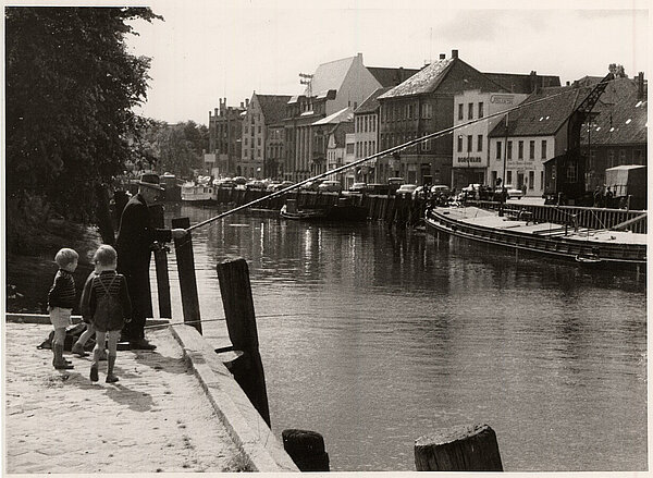 Ein Angler fischt am Stau. Das Gebäude ganz links ist der Handelshof, der 1967 abgerissen wurde. Ohne Jahr. Bild: Stadtmuseum Oldenburg.