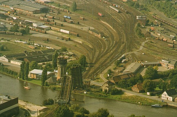 Luftbild mit Blick auf Wasserturm, Rollklappbrücke und Gleisanlagen, das neue Dach liegt neben dem Turm, Anfang der 1990er Jahre, Foto: Stadtmuseum Oldenburg